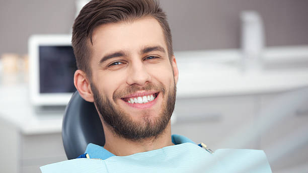 Man smiling in a dentist chair, after treatment