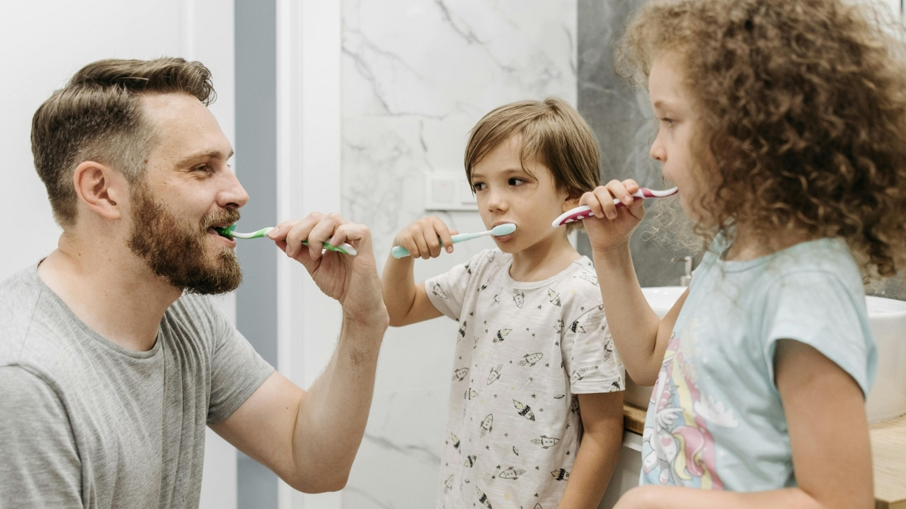 a father brushing his teeth with his two children